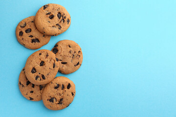 Many delicious chocolate chip cookies on light blue background, flat lay. Space for text
