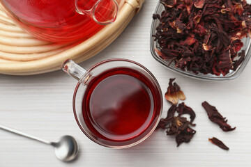 Delicious hibiscus tea and dry flowers on white wooden table, flat lay