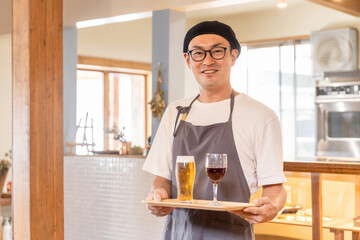 居酒屋・飲食店で働くビール・ワインを運ぶスタッフ・従業員の男性
