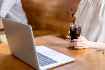 カフェでコーヒーを飲みながらリモートワークするアジア人女性
