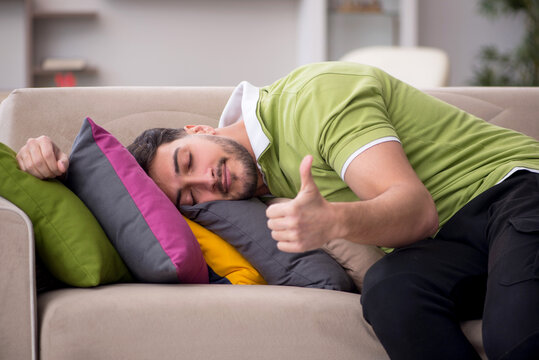 Young man with a lot of pillows sitting on the sofa