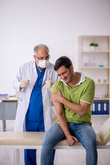 Young male patient visiting old male doctor in vaccination conce