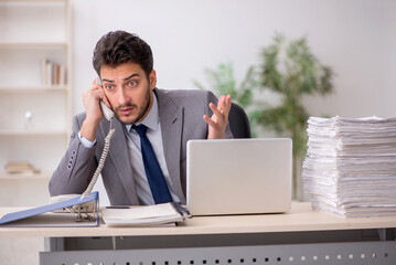 Young male employee and too much work in the office