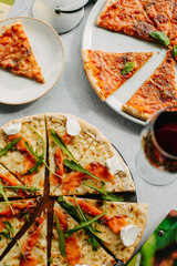 Traditional Italian pizza, vegetables, ingredients on a light background.Top view. a piece of pizza in the hand.Festive table. company of friends