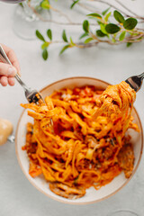 Italian pasta, tomato sauce. Two female hands in the frame, girls eat pasta, hold forks in their hands, top view, Italian cuisine.