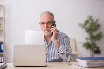 Old male employee working at workplace