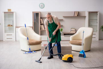 Old male contractor cleaning the house