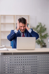 Young male employee sitting at workplace