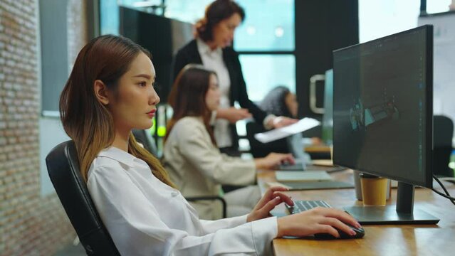 Asian woman is designing a 3D electric vehicle at her office, utilizing her knowledge of 3D modeling software which she acquired through her studies in a classroom setting.