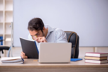 Young male teacher sitting in the classroom