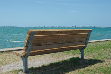 Naklejka na ściany i meble Back View of Park Bench looking out over bay water empty no people. Room for copy.