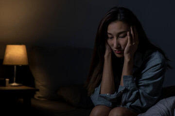Fototapeta na wymiar Young Asian woman in bedroom feeling sad tired and worried suffering depression in mental health, woman sitting in bed cannot sleep from insomnia.