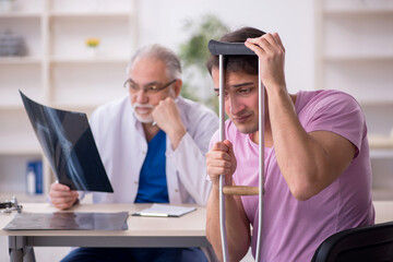 Young leg injured patient visiting old male doctor radiologist