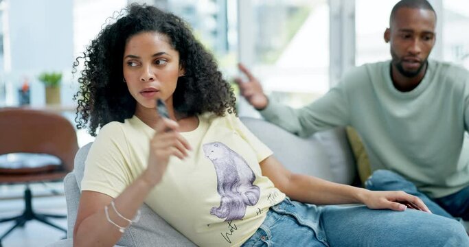 Couple, nicotine and argue about addiction with a woman smoking an e cigarette in the living room of her home. Smoke, habit and lifestyle with an attractive young female smoker in her house to relax