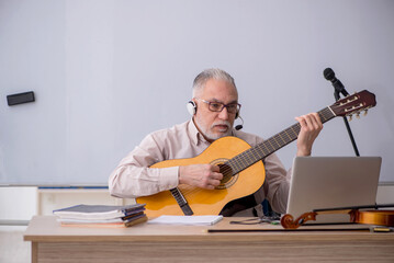 Old male music teacher in the classroom