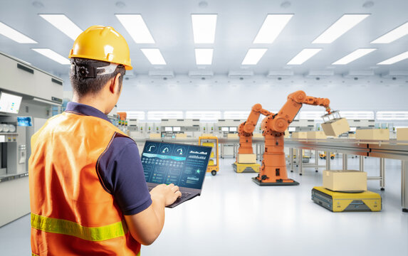 Technician or engineer with robotic arms in factory