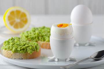 Soft-boiled egg and open bread sandwich with avocado on the table. Traditional food for a healthy breakfast.