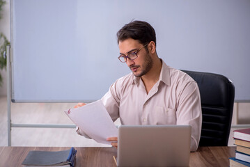 Young male teacher sitting in the classroom