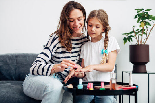 Mother and daughter doing manicure at home, painting nails with nail polish