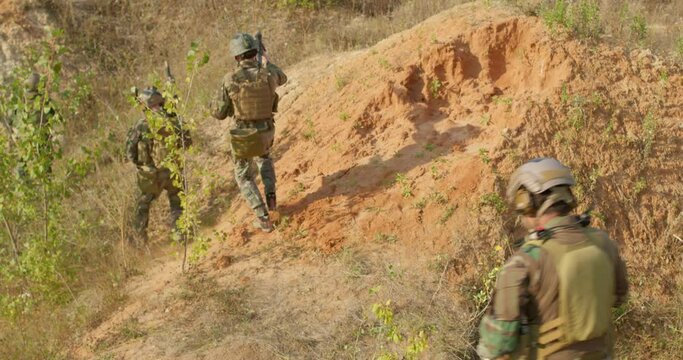 young group of soldiers is taking part in Military Mission running soldiers are going down hill, young people are rushing to help friends to fight with enemies slow motion