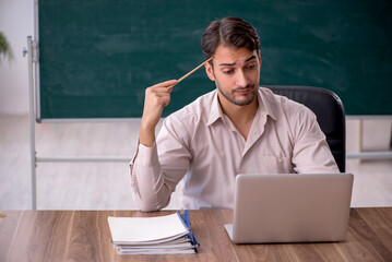 Young male teacher sitting in the classroom