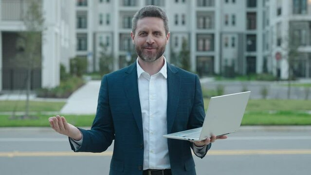 Portrait of happy and successful middle age handsone businessman or business man in formal suit working on laptop outdoor.