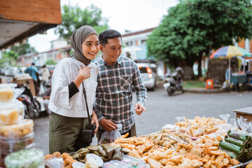 beautiful muslim couple are shopping in a food stall or street vendor during ramadan
