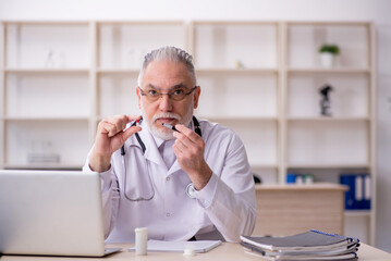 Old male doctor suggesting pills in the clinic