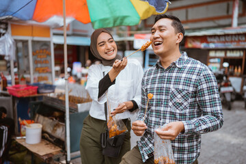 couple have fun enjoying snacks from street vendor shop during fasting in ramadan