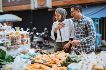 beautiful muslim woman and man are shopping in a food stall or street vendor during ramadan - obrazy, fototapety, plakaty