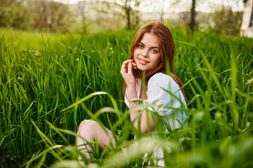 happy smiling redhead woman resting sitting in tall grass