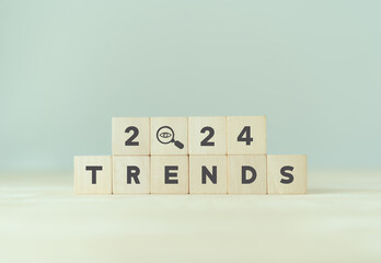 2024 trend concept. Wooden cube with 2024, magnifying glass, TRENDS text. Beautiful grey background, copy space. Used for banner in trend concept in new year for monitoring new business opportunities.