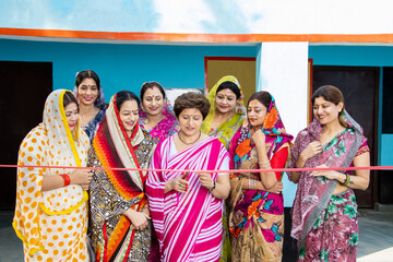 Fototapeta na wymiar Indian business woman in sari cutting red ribbon while colleagues are clapping hands. Women empowerment.
