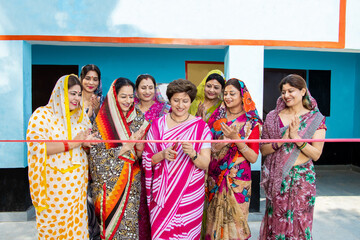 Fototapeta na wymiar Indian business woman in sari cutting red ribbon while colleagues are clapping hands. Women empowerment.
