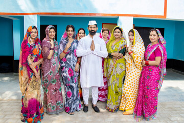 Indian man politician standing doing namaste with group of traditional women. Concept of election and vote. - obrazy, fototapety, plakaty