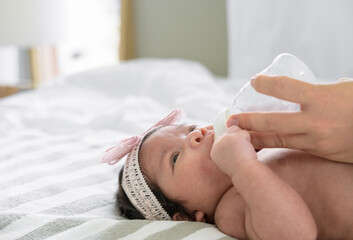 Obraz na płótnie Canvas Newborn baby girl or boy drinking milk from bottle