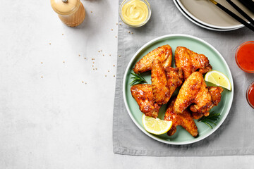 Air fryer chicken wings glazed with hot chilli sauce and served with different sauces.  gray background . top view