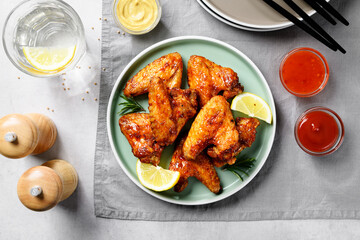 Air fryer chicken wings glazed with hot chilli sauce and served with different sauces.  gray...