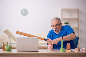 Old male dentist working in the clinic
