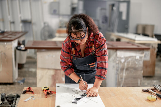 A Carpenter carefully measures, marks dimensions, and lays out reference lines on wood using scribe, divider, square, ruler, and caliper. The woodworking process need skills, experience, precision.