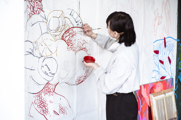 Female artist drawing painting with paint brush and black paint. Graphic Painting. Creating modern Art
