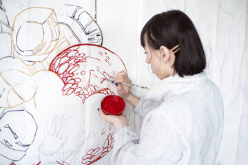Female artist drawing painting with paint brush and black paint. Graphic Painting. Creating modern...