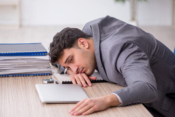 Obraz premium Young male employee and too much work in the office