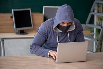 Young male hacker sitting in the classroom