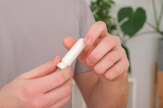 Adult man uses nasal stick inhaler to smell for relieve dizzy and faint symptoms.