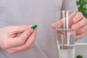 Caucasian man taking a pill and drinking a glass of water. Health, medicine, treatment concept.