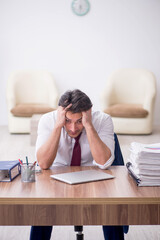 Young male employee unhappy with excessive work in the office