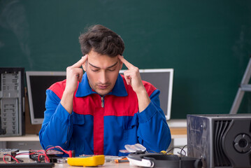 Young male repairman repairing computers in the classroom