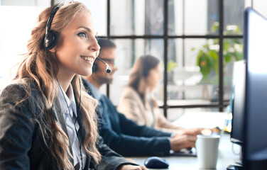 Portrait of call center worker accompanied by her team. Smiling customer support operator at work.