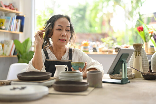 A retired potter woman using a tablet to sell pottery online, SME business ideas online.